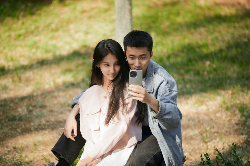 户外公园里用手机自拍的年轻情侣图片