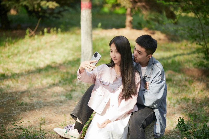 户外公园里用手机自拍的年轻情侣图片