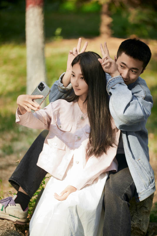 户外公园里用手机自拍的年轻情侣图片