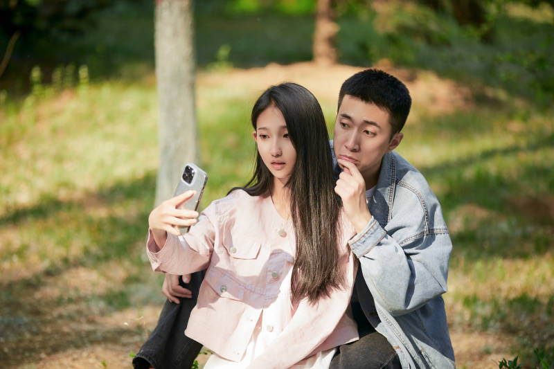 户外公园里用手机自拍的年轻情侣图片