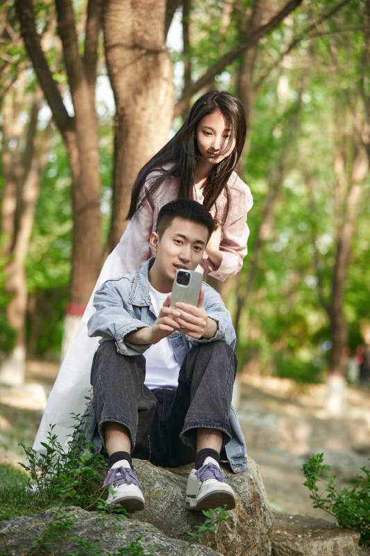 户外公园里用手机自拍的年轻情侣图片