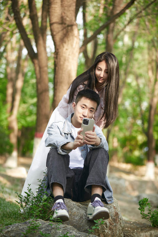 户外公园里用手机自拍的年轻情侣图片