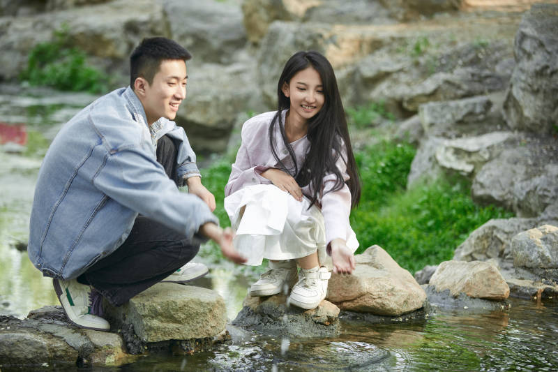 在公园小溪旁嬉戏玩水的青年情侣图片