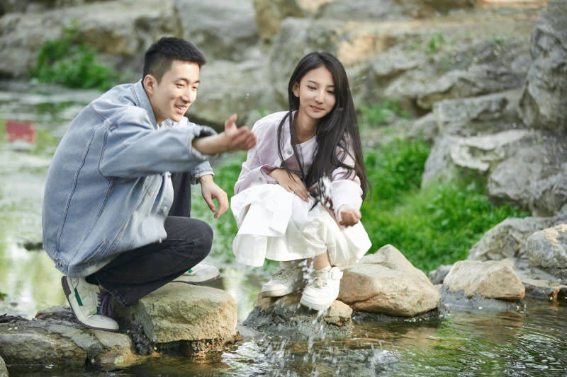 在公园小溪旁嬉戏玩水的青年情侣图片