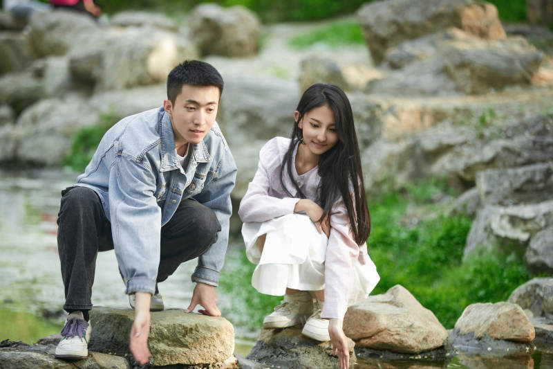 在公园小溪旁嬉戏玩水的青年情侣图片