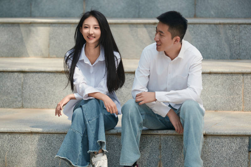 坐在户外台阶上的青年情侣图片