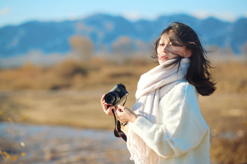 深秋户外手持相机的亚洲女性摄影师图片