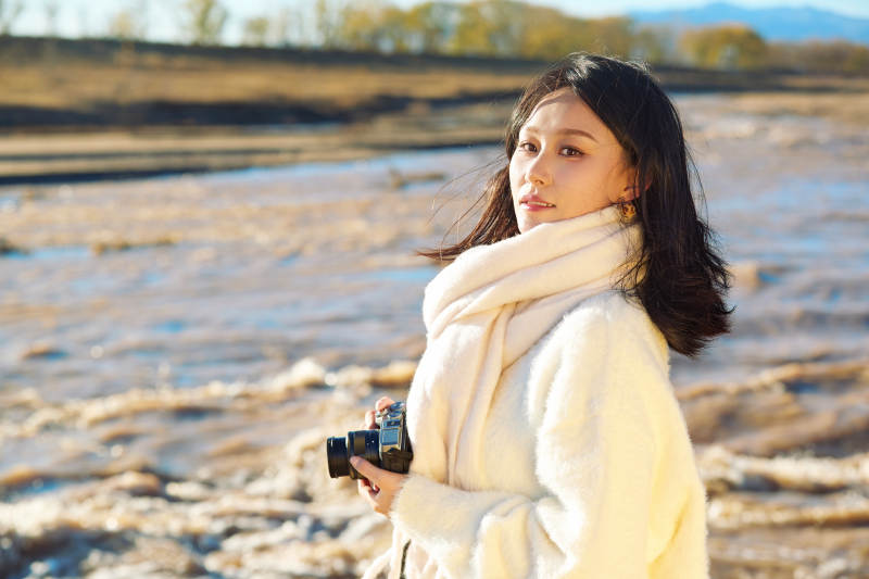深秋户外手持相机的亚洲女性摄影师图片