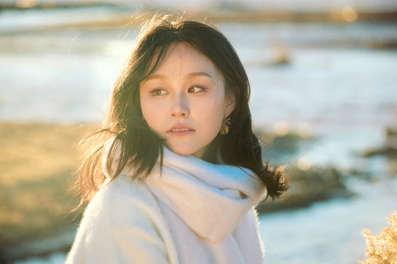 秋天在夕阳下的原野河边拍照的美女图片