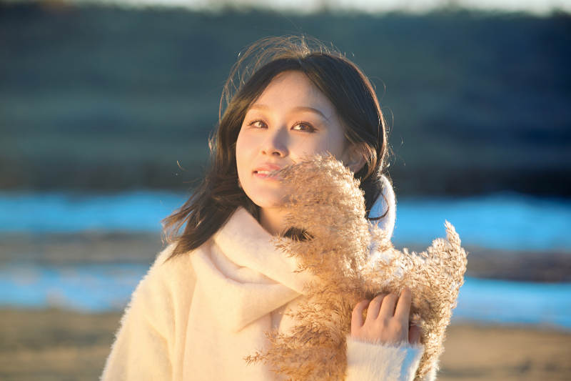 秋天在夕阳下的原野河边拍照的美女图片