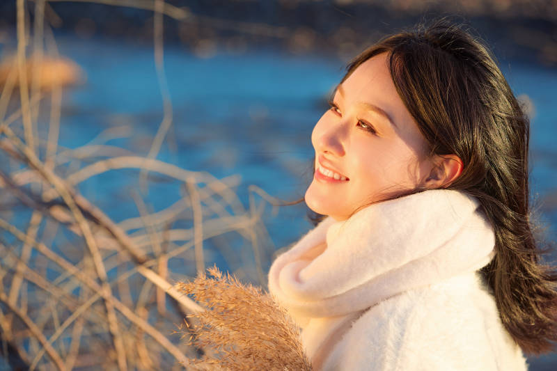 秋天在夕阳下的原野河边拍照的美女图片