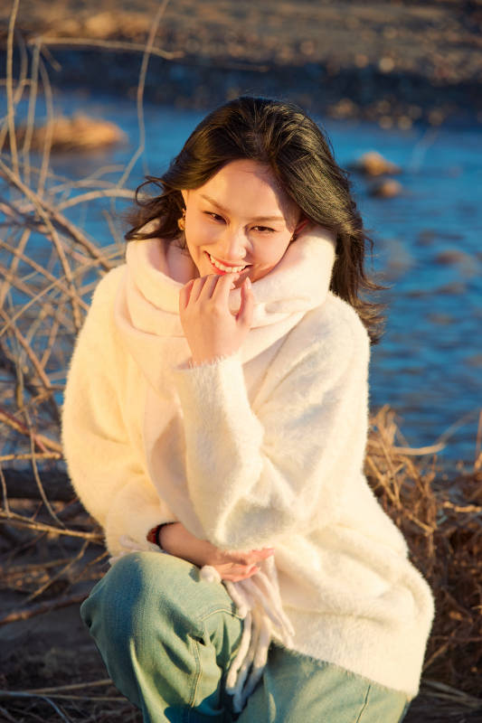 秋天在夕阳下的原野河边拍照的美女图片