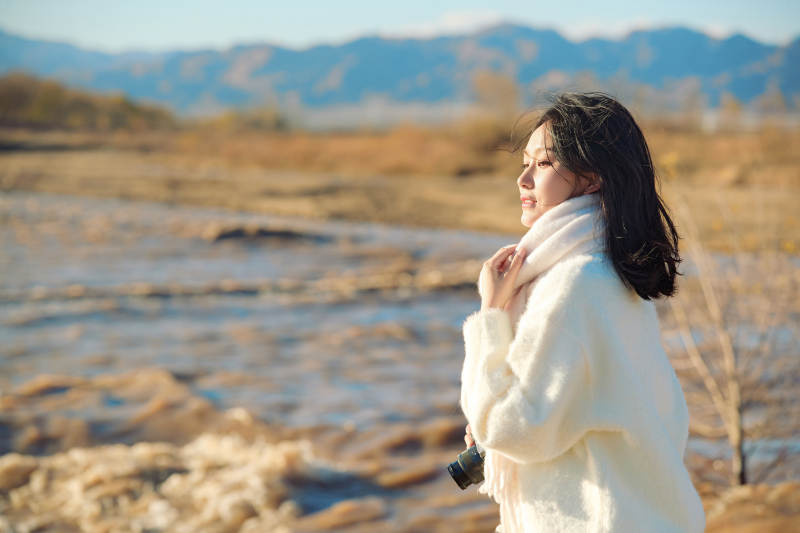 拿着相机的美女摄影师在深秋的户外拍摄图片