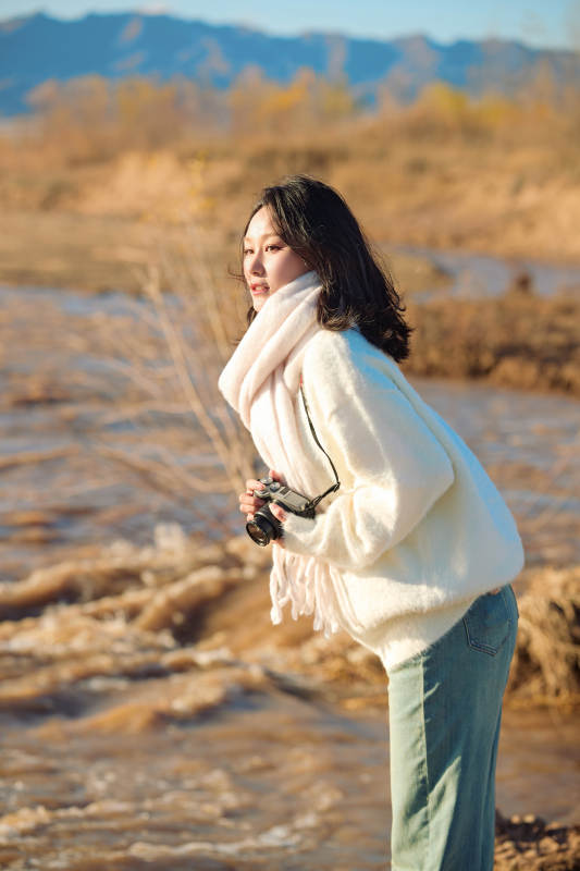 拿着相机的美女摄影师在深秋的户外拍摄图片