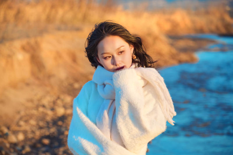 深秋夕阳下在户外河水边的东方女性图片