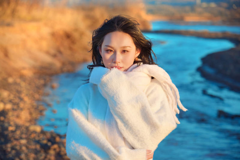 深秋夕阳下在户外河水边的东方女性图片