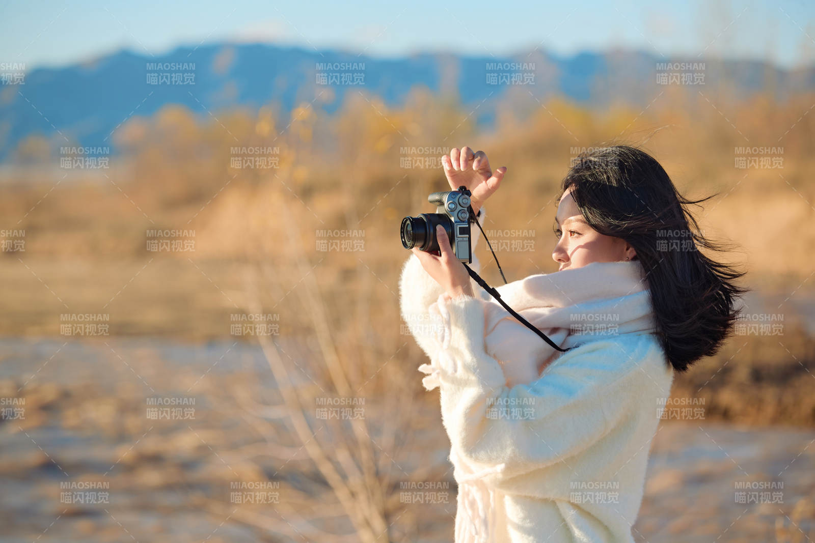 拿着相机的美女摄影师在深秋的户外拍摄图片