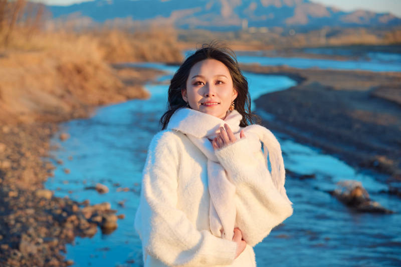 深秋夕阳下在户外河水边的东方女性图片