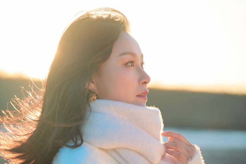 深秋夕阳下在户外河水边的东方女性图片