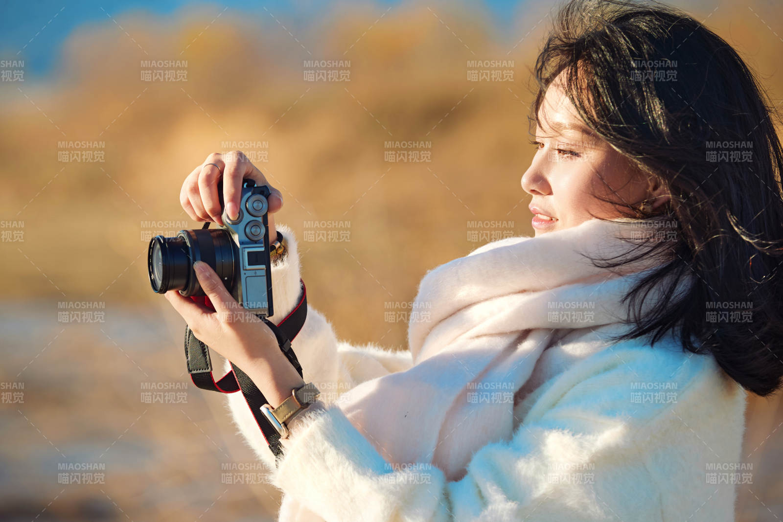 拿着相机的美女摄影师在深秋的户外拍摄图片