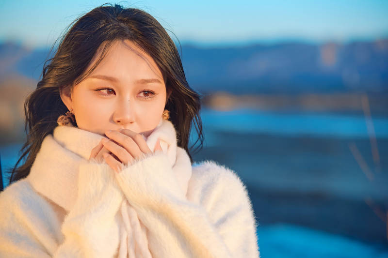 深秋夕阳下在户外河水边的东方女性图片