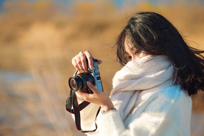 拿着相机的美女摄影师在深秋的户外拍摄图片