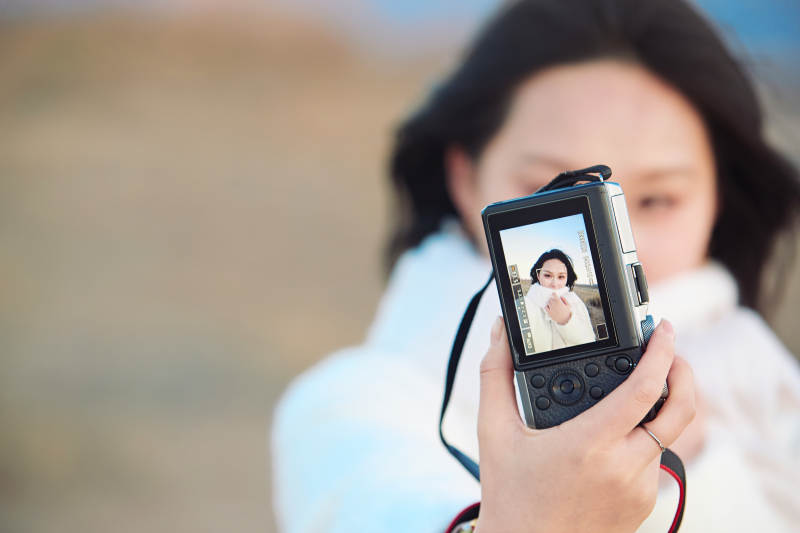 秋天夕阳下手持相机自拍的亚洲美女图片