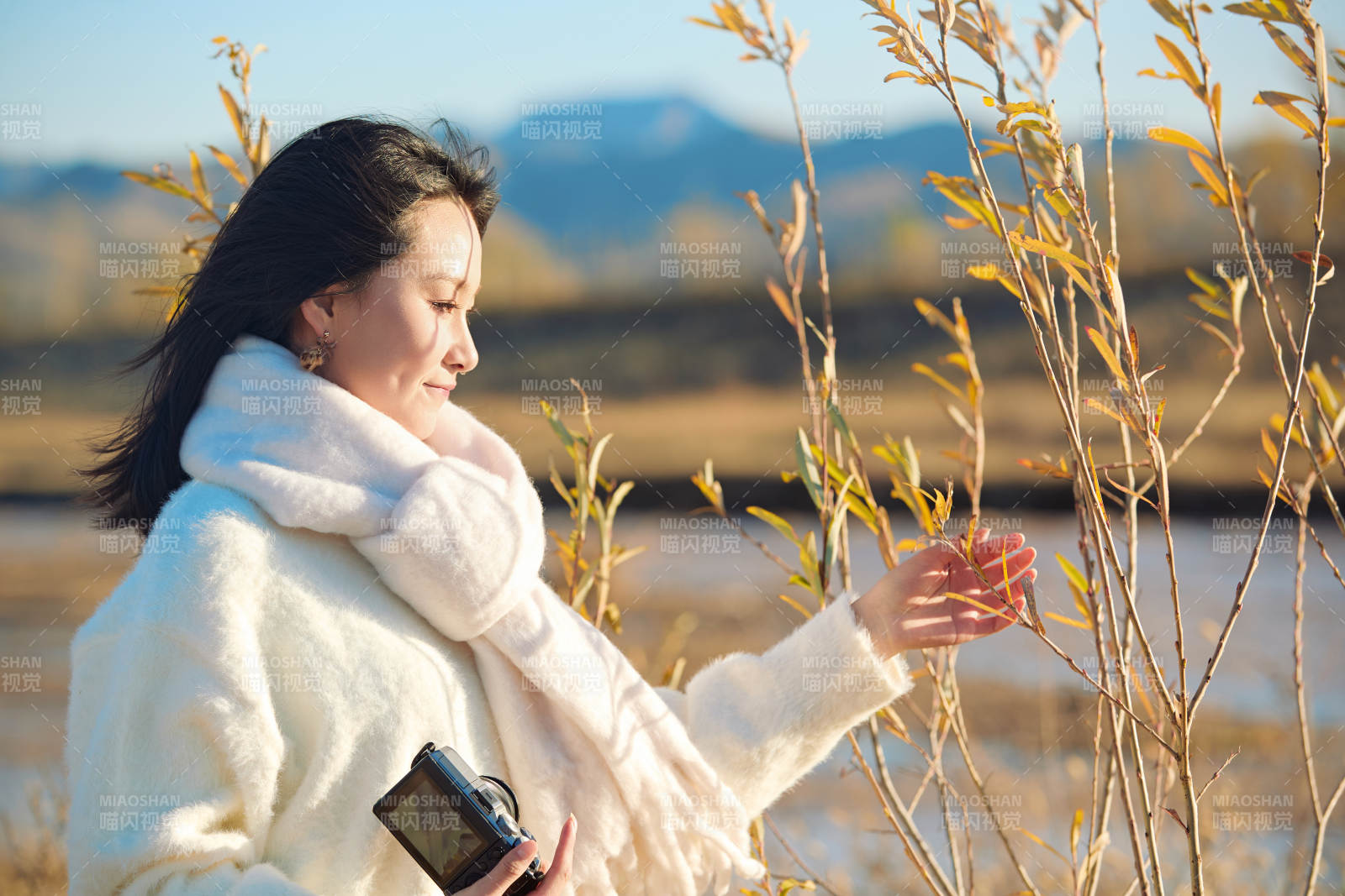 拿着相机的美女摄影师在深秋的户外拍摄图片