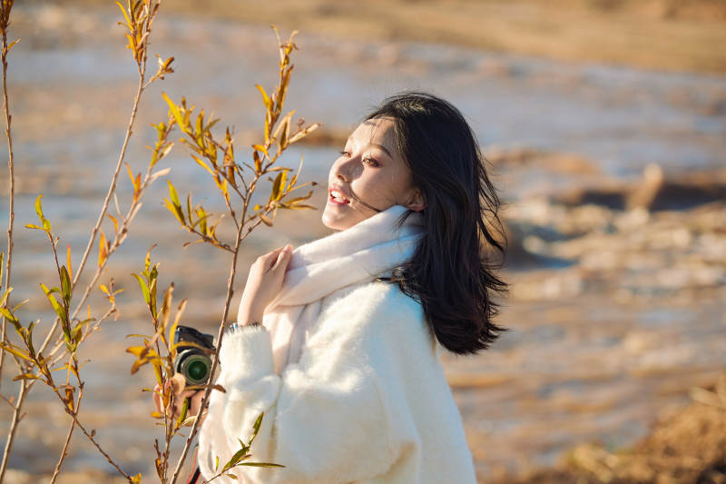 拿着相机的美女摄影师在深秋的户外拍摄图片