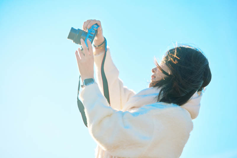 拿着相机的美女摄影师在深秋的户外拍摄图片