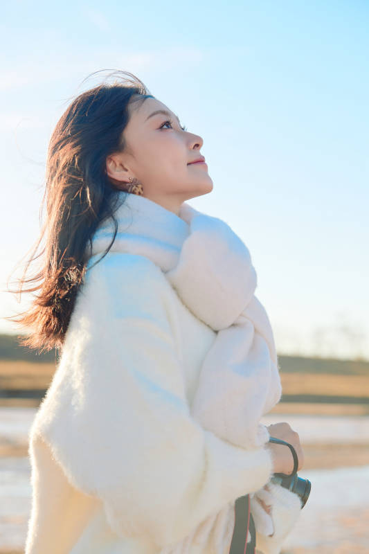 拿着相机的美女摄影师在深秋的户外拍摄图片