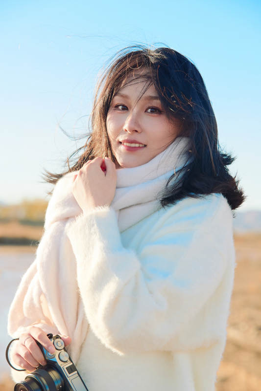 拿着相机的美女摄影师在深秋的户外拍摄图片