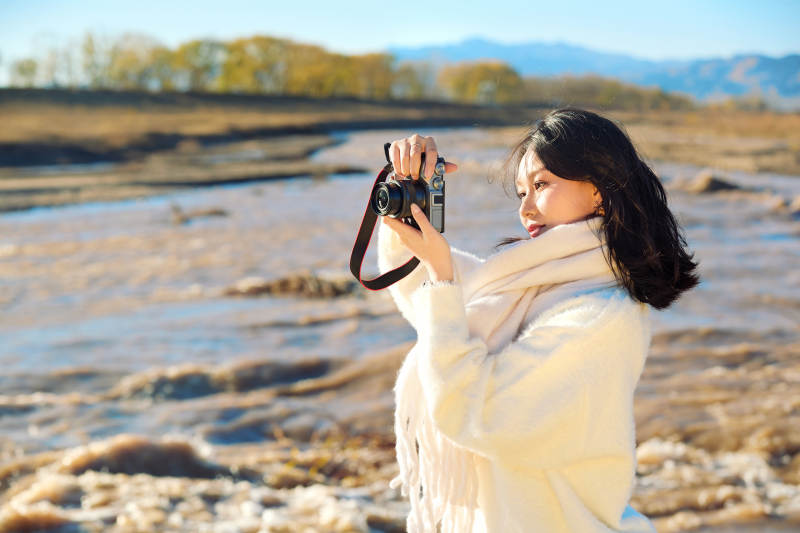 深秋户外手持相机的亚洲女性摄影师图片