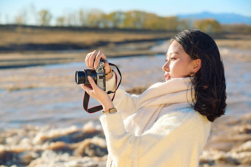 深秋户外手持相机的亚洲女性摄影师图片