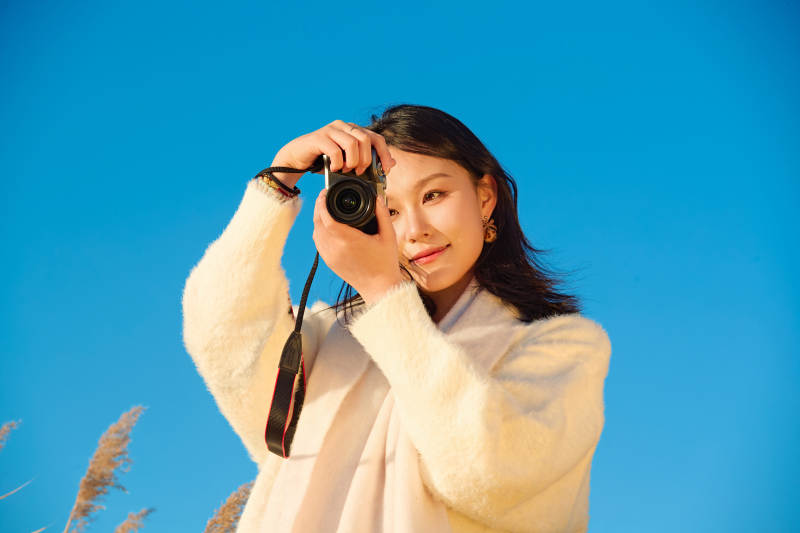 秋天晴朗的午后在芦苇荡里拍照的女性摄影师图片