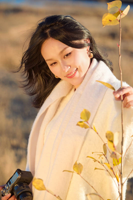 秋天晴朗的午后在芦苇荡里拍照的女性摄影师图片