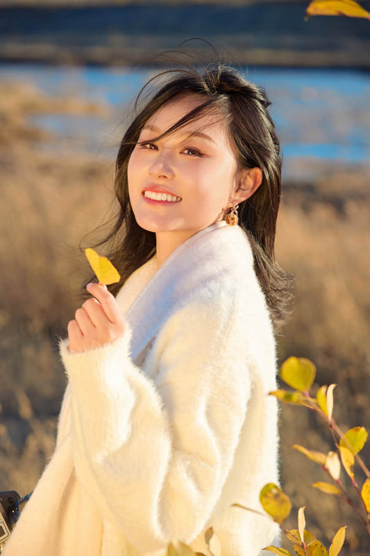 秋天晴朗的午后在芦苇荡里拍照的女性摄影师图片