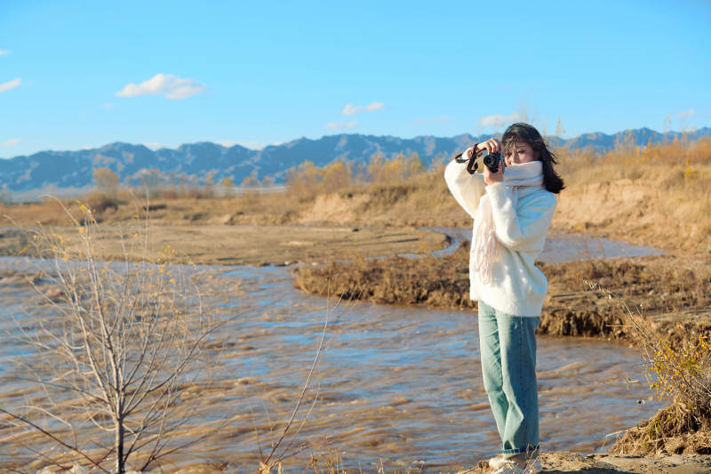 深秋户外手持相机的亚洲女性摄影师图片