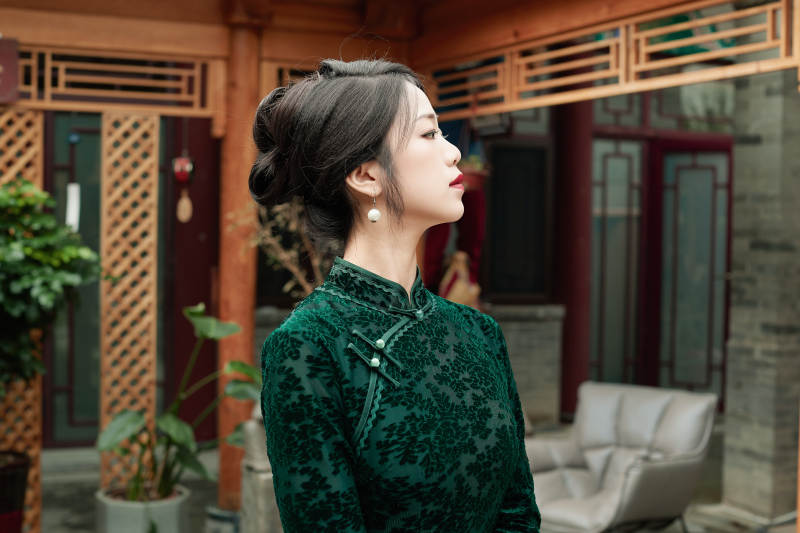 身穿旗袍在庭院散步的年轻美女图片