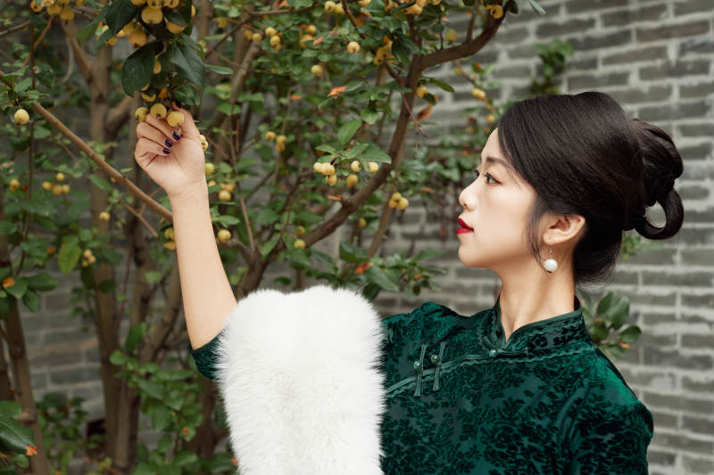 身穿旗袍在庭院散步的年轻美女图片