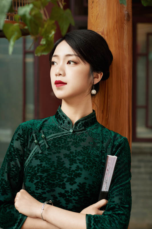 身穿旗袍在庭院散步的年轻美女图片