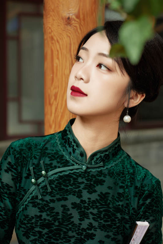 身穿旗袍在庭院散步的年轻美女图片