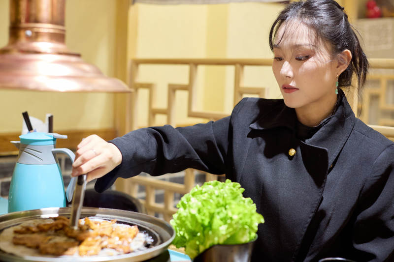 在韩式烤肉店享受美食的亚洲美女图片