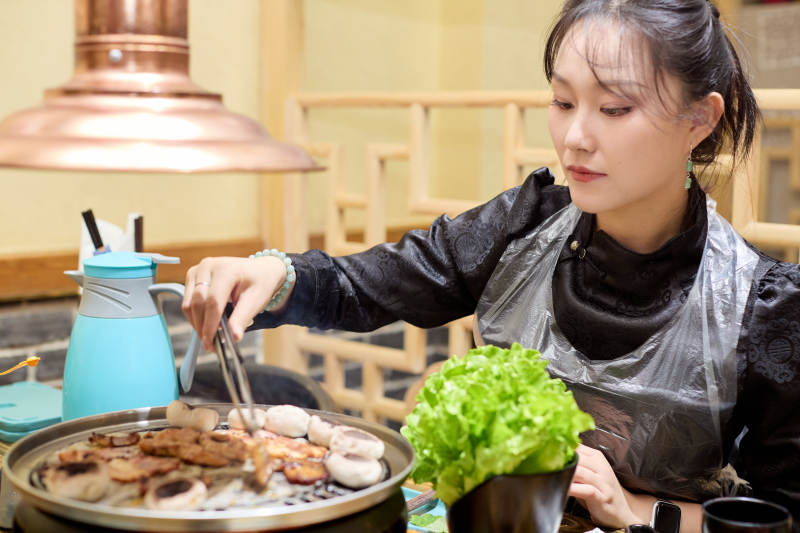在韩式烤肉店享受美食的亚洲美女图片