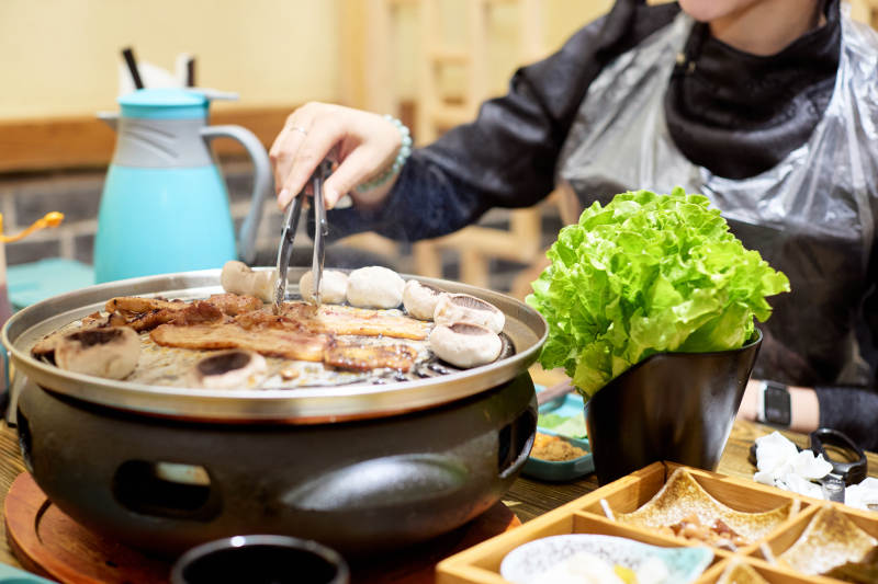 在韩式烤肉店享受美食的亚洲美女图片