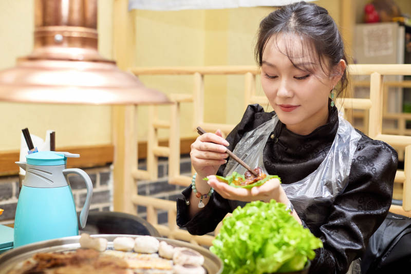 在韩式烤肉店享受美食的亚洲美女图片