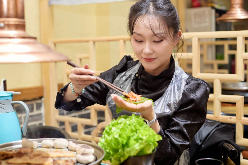 在韩式烤肉店享受美食的亚洲美女图片