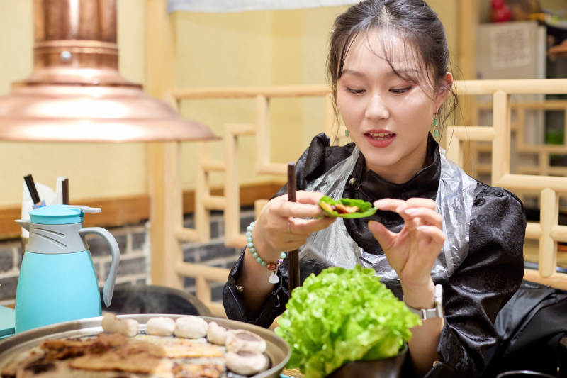 在韩式烤肉店享受美食的亚洲美女图片