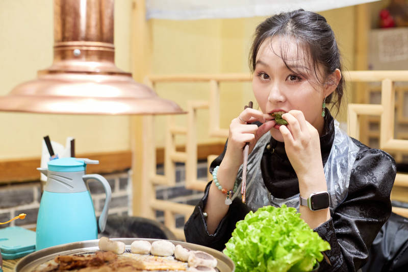 在韩式烤肉店享受美食的亚洲美女图片