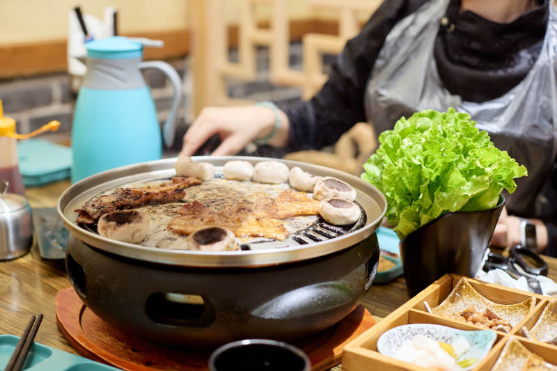 在韩式烤肉店享受美食的亚洲美女图片